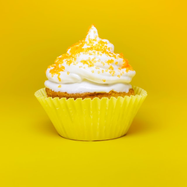 cupcake with white frosting against a yellow background