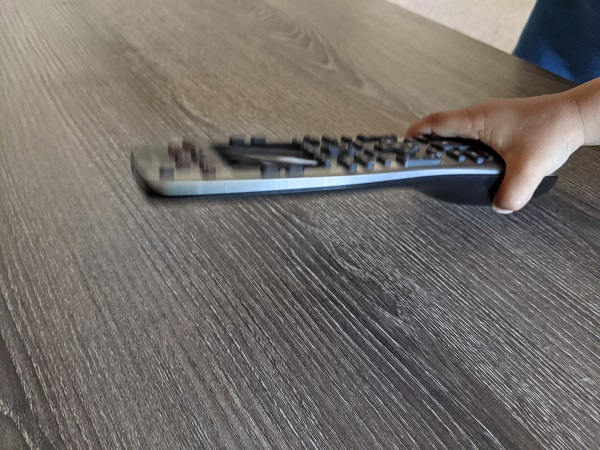 child's hand holding a TV remote control