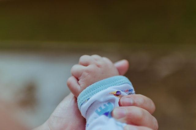 adult hand holding infant hand. some parents worry about night weaning due to cavity concerns.