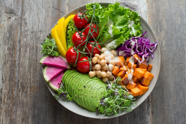 bowl of fresh produce including sliced cucumber, chickpeas, lettuce, and tomatoes. Example of a meal from a variety of plants, ideal for improving gut microbiome