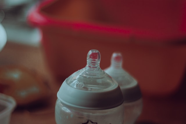 2 baby bottles, the tops visible with red container in the background