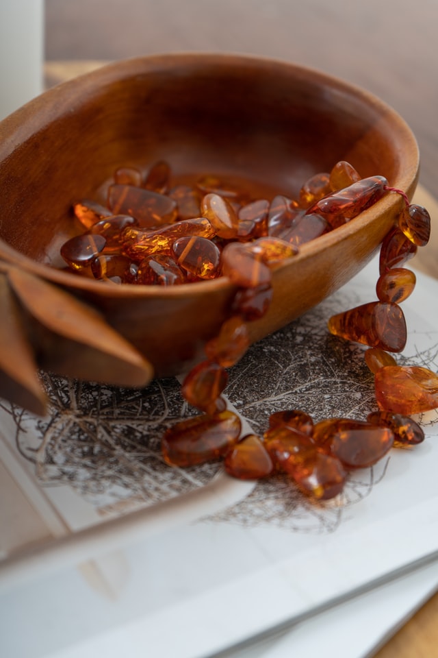 beaded amber necklace resting in a wooden bowl