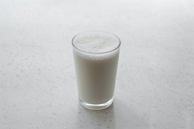 photo of a small glass of cow's milk against white background